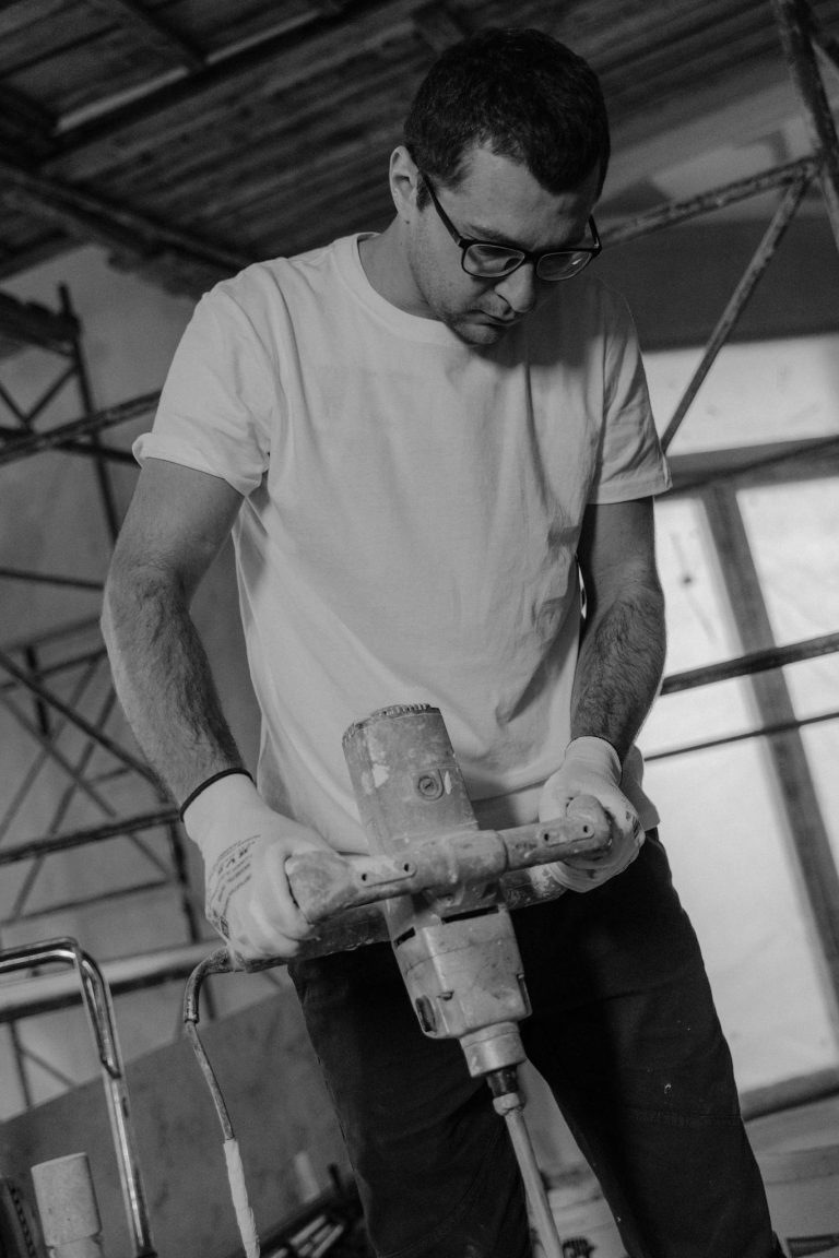 Focused construction worker operating a drill in an industrial setting.